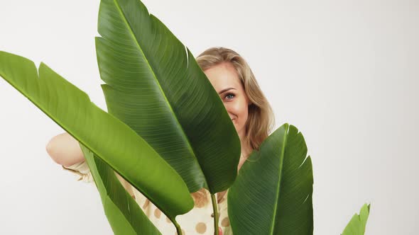 Charming European Blueeyed Blonde Girl with a Pretty Smile Stands Behind the Green Leaves Medium