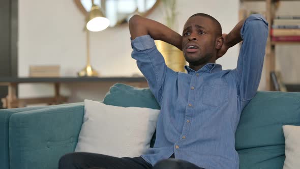 Anxious Young African Man Feeling Worried Sitting on Sofa 