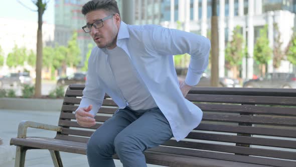 Man Having Back Pain While Sitting on Bench Outdoor