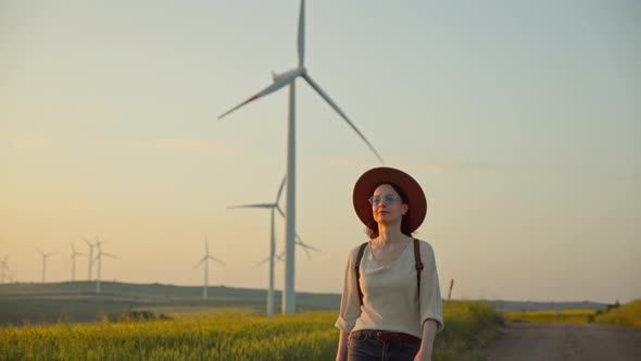 Attractive tourist walking near a field with alternative green energy windmills