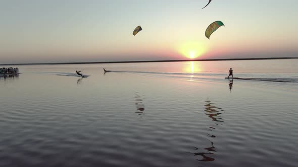 Aerial Footage of Kite Surfers Gliding on a Pink Lake During Sunset, 