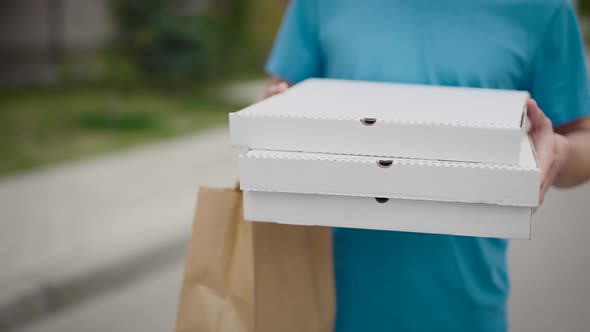 An Unrecognizable Food Delivery Man Carries Pizza Boxes and Food Bags