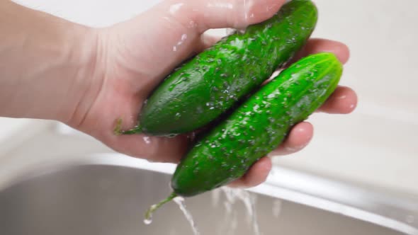 Rinsing Green Cucumbers Under Running Water in Hands Closeup
