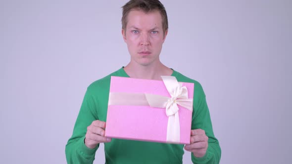 Young Handsome Man Looking Shocked with Gift Box