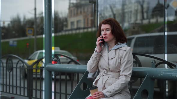 Woman Talking on Phone at Bus Stop in Rainy Weather