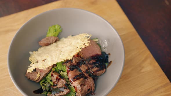 Close-up of Bowl of Cooked Food Meat and Vegetables on Wooden Table in Kitchen