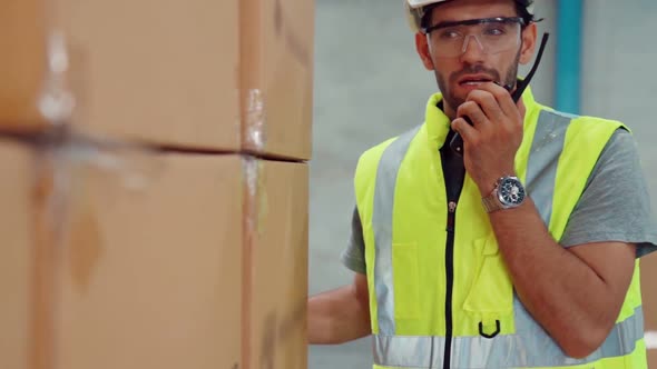 Professional Cargo Worker Talks on Portable Radio to Contact Another Worker