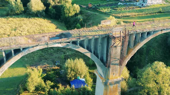 A Lady Is Jogging Along a Large Old Bridge