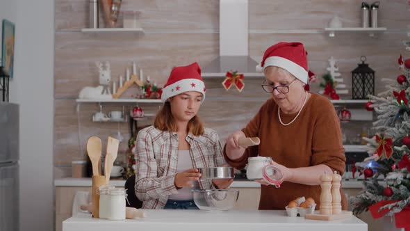 Grandchild Helping Senior Woman Preparing Homemade Traditional Cookie Dough