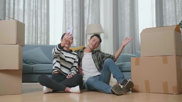 Young Asian Couple With Cardboard Boxes Smartphone After Moving Into A New House 