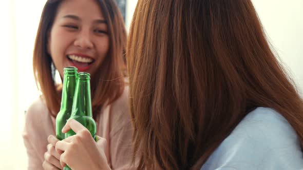 Young Asian young woman clinking bottles of beer in the bedroom.