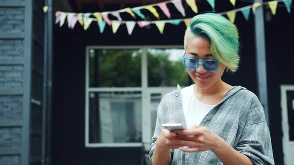 Asian Girl Using Smartphone Touching Screen Outdoors Enjoying Social Media