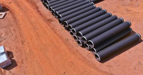 There are Rows of New Black Plastic PVC Pipes Stacked in Rows for Drain Systems at a Construction