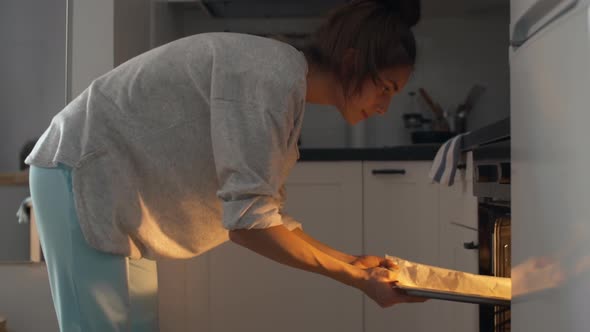 Woman Putting Baking Pan into Oven