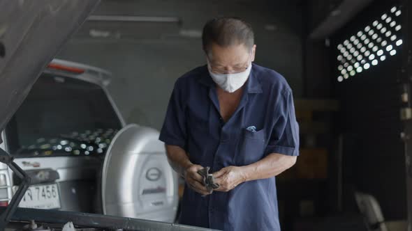 Asian Auto Mechanic At Work Wearing Mask And Eyeglasses In Mechanical Shop