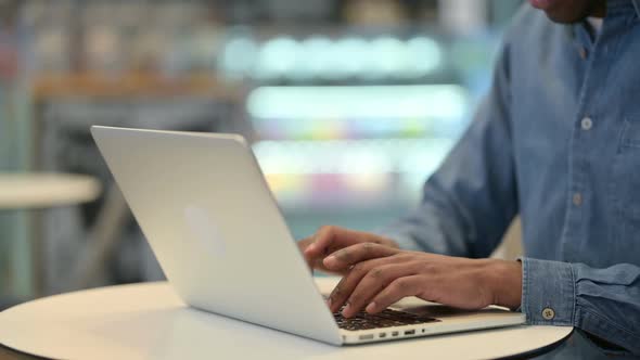 African Man Typing on Laptop Keyboard Close Up