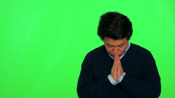 A Young Asian Man Prays with Hands Clasped Together - Green Screen Studio
