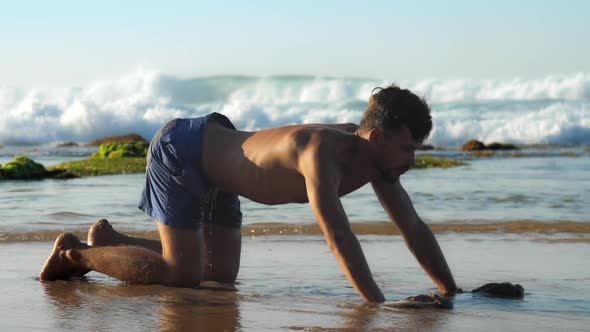 Muscular Bearded Man Does Yoga Stretching in Shallow Water