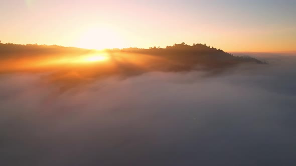 4K Aerial view flying in fog. the sun is hidden behind the clouds at sunset fog.