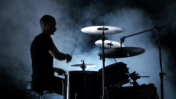 Professional Musician Plays Music on Drums . Smoky Background. Side View. Silhouette. Back Light