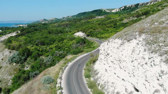 Winding Road On White Hill Coast With Dense Vegetation In Balchik, Bulgaria. aerial drone ascend