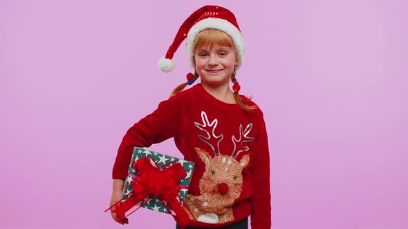 Cheerful Girl in Santa Sweater Presenting Two Christmas Gift Boxes Stretches Out Her Hands to Camera