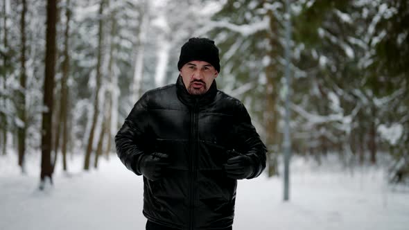 Middle Aged Man is Keeping Fit and Running in Winter Morning in Forest Portrait of Sporty Person