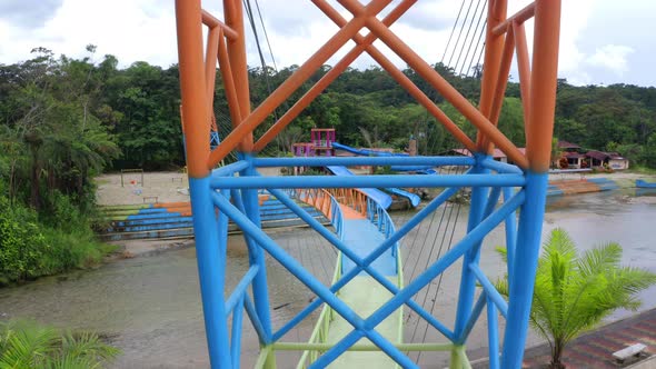 Looking between the colorful metal posts of a steel pedestrian bridge painted in red green and blue