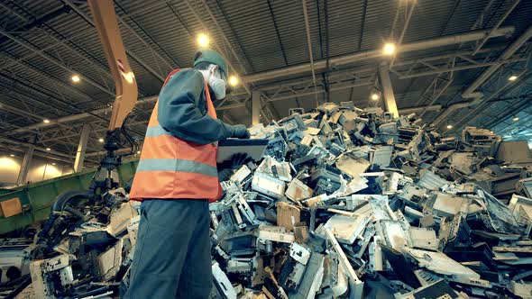 Fragments of Office Machine in a Dumpsite Unit with a Worker