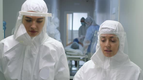 Nurses in Protective Suits Speaking while Walking in Hospital