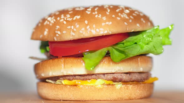 Male Hand Putting Bun Sprinkled with Sesame on Top of Juicy Tasty Burger Closeup