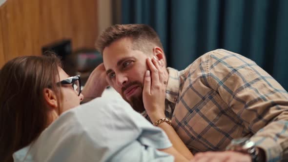 A young couple lies in bed in a hotel room and strokes each other