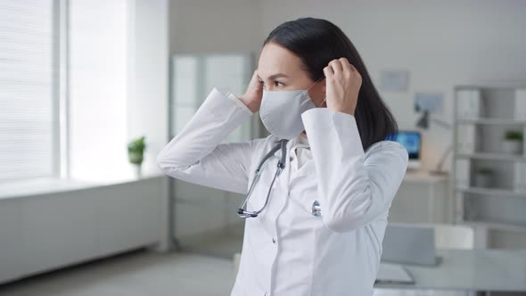 Woman Working In Hospital Putting On Mask