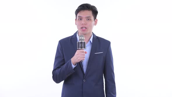 Happy Young Asian Businessman As Newscaster Using Microphone