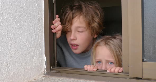 Sister and Brother Looking Outside Through the Open House Window