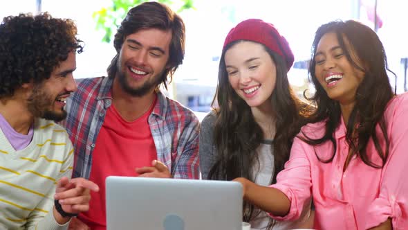 Friends laughing while looking at laptop