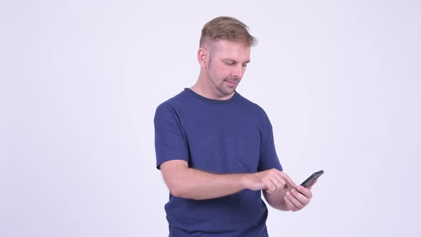 Portrait of Happy Blonde Man Using Phone and Getting Good News