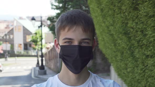 Young man laughs and takes off a black medical protective mask 