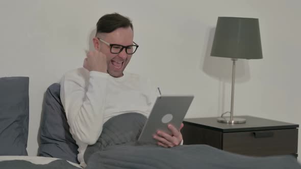 Casual Man Celebrating Success on Tablet in Bed