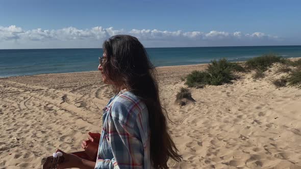 Girl Vacationer Enjoying Summer Heat on the Beach and Playing Ukulele