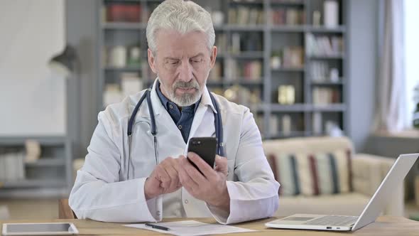 Senior Old Doctor Using Smartphone in Clinic