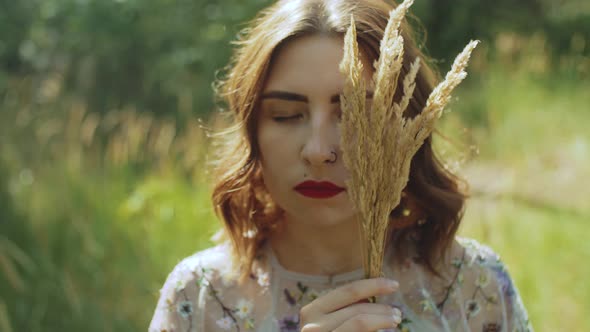 Closeup Portrait of an Attractive Woman with Closed Eyes and a Bouquet of Spikelets in Her Hands