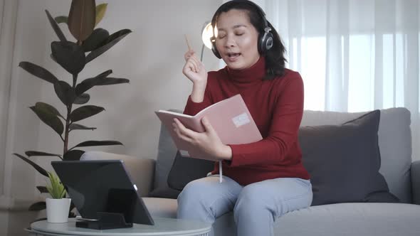 Freelance woman redshirt using tablet with headphone for meeting online at home