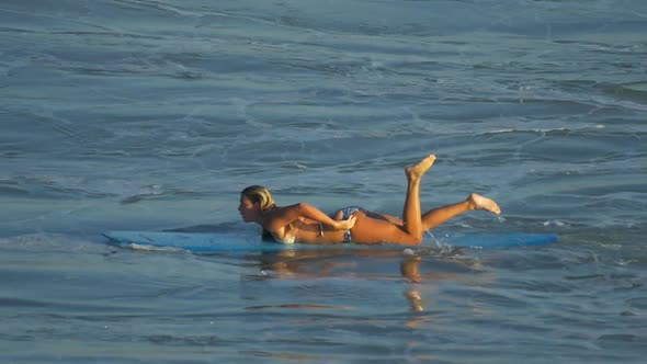 A young woman surfing in a bikini on a longboard surfboard.