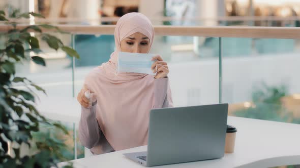 Funny Arab Woman Sitting in Public Place Uses Antiseptic Sprinkles Around in Air on Laptop Covers