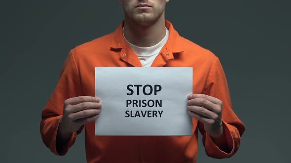 Stop Prison Slavery Phrase on Cardboard in Hands of Caucasian Prisoner, Problem