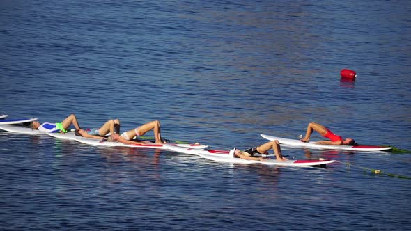 Group of Young Womens in Swimsuits Doing Yoga and Pilates on Sup Board in Calm Sea Early Morning