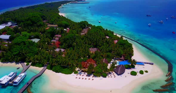 Wide birds eye tourism shot of a sandy white paradise beach and blue water background in hi res 4K