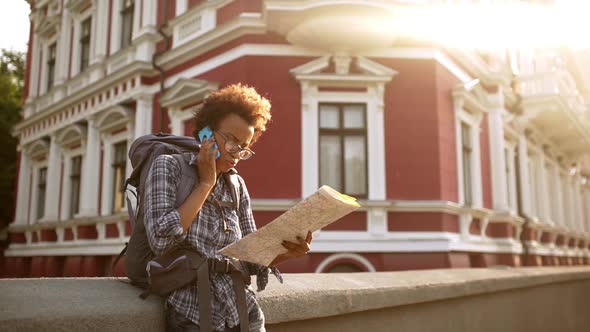 Beautiful African Girl Speaking on Phone Can't Find Route at Map with Sun Behind Her Slow Motion