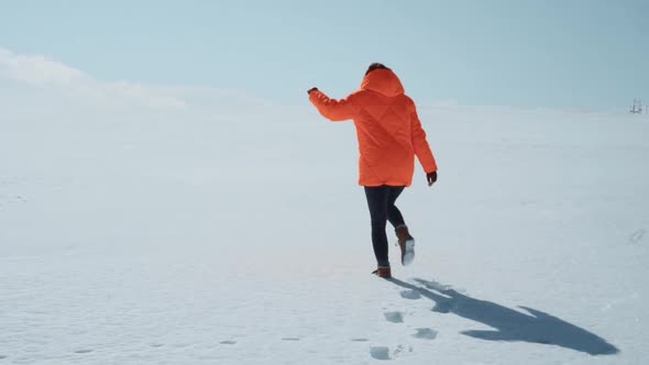 a Girl Walks Through a Snowy Field During the Day